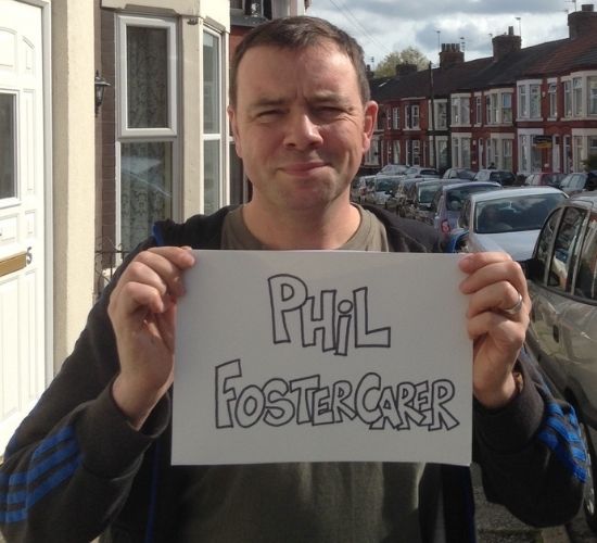 Fostering Phil holding a sign with is name sign