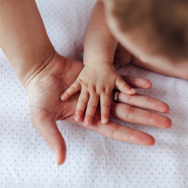 Baby and carer touching hands