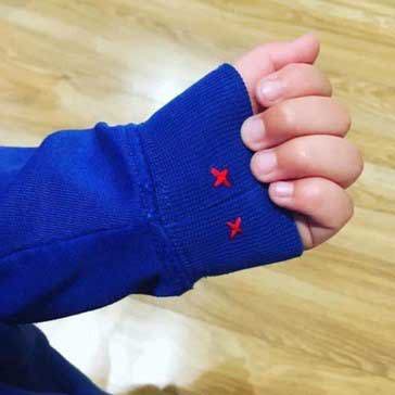 Small red crosses sown onto child's jumper cuff