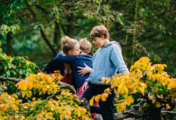 Two birth siblings together with young person hugging