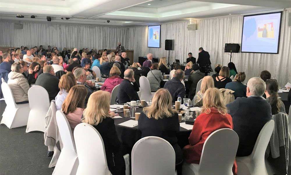 People seated at large round tables at fostering event