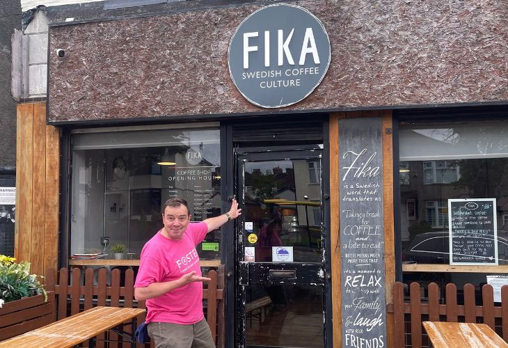 Fostering Phil outside and pointing at Fika Swedish Coffee House 