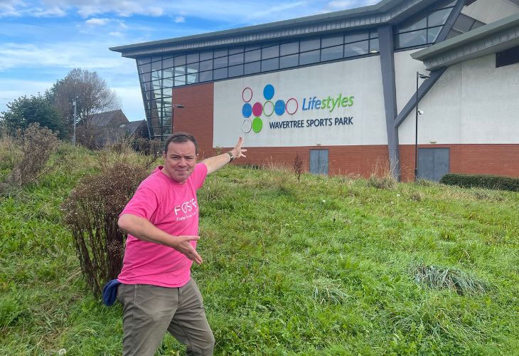 Foster carer Phil pointing at Wavertree Sports Park building