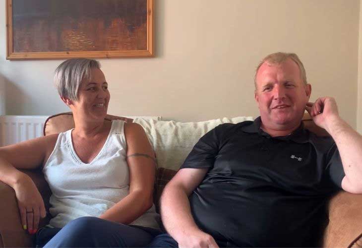 Foster carers Sarah and Kevin sitting on sofa and smiling