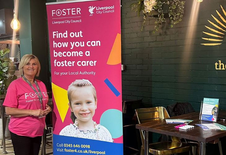 Member of the fostering Liverpool team standing next to pop-up banner in Taskers Bistro