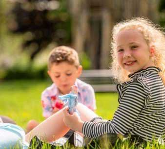 Two children eating ice cream sitting on grass